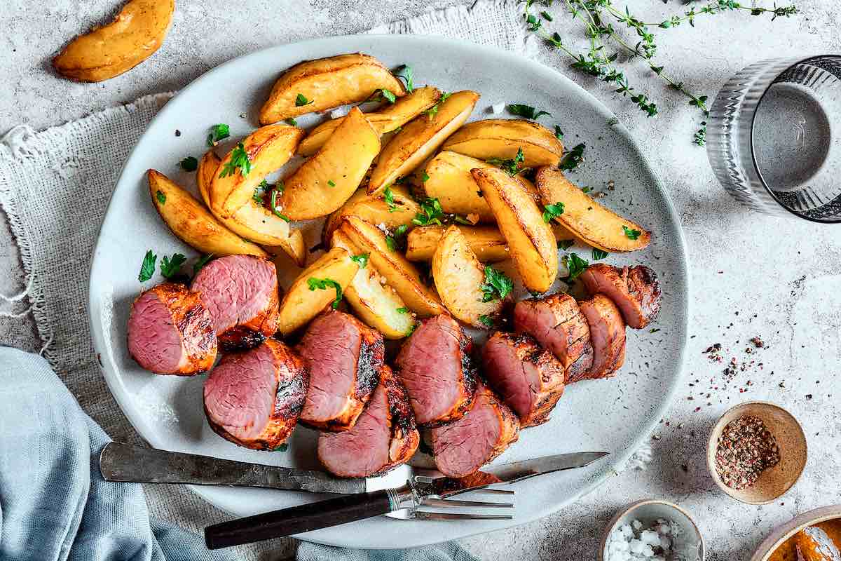 sliced grilled pork tenderloin with potatoes.