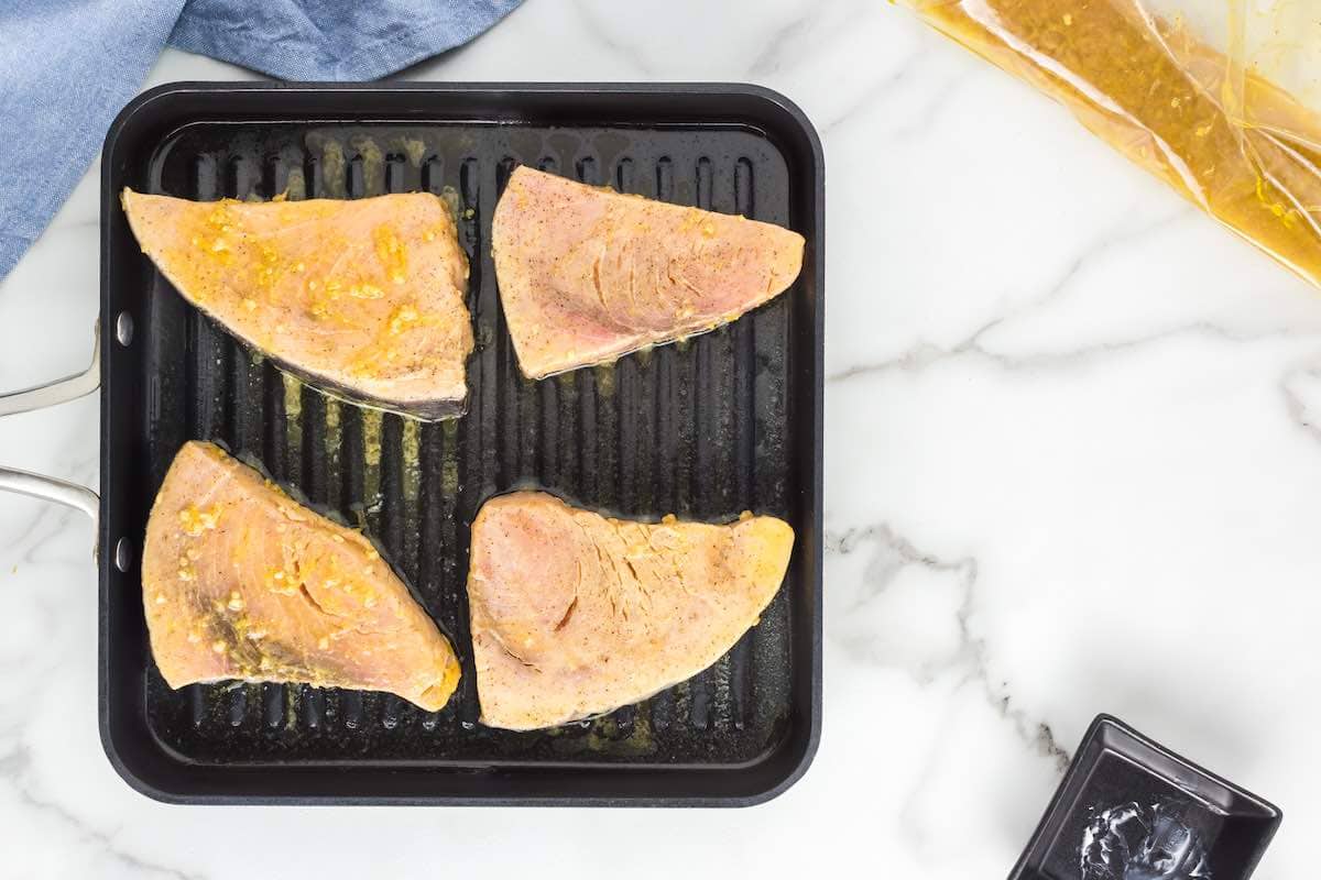 seasoned raw swordfish fillets on the grill.