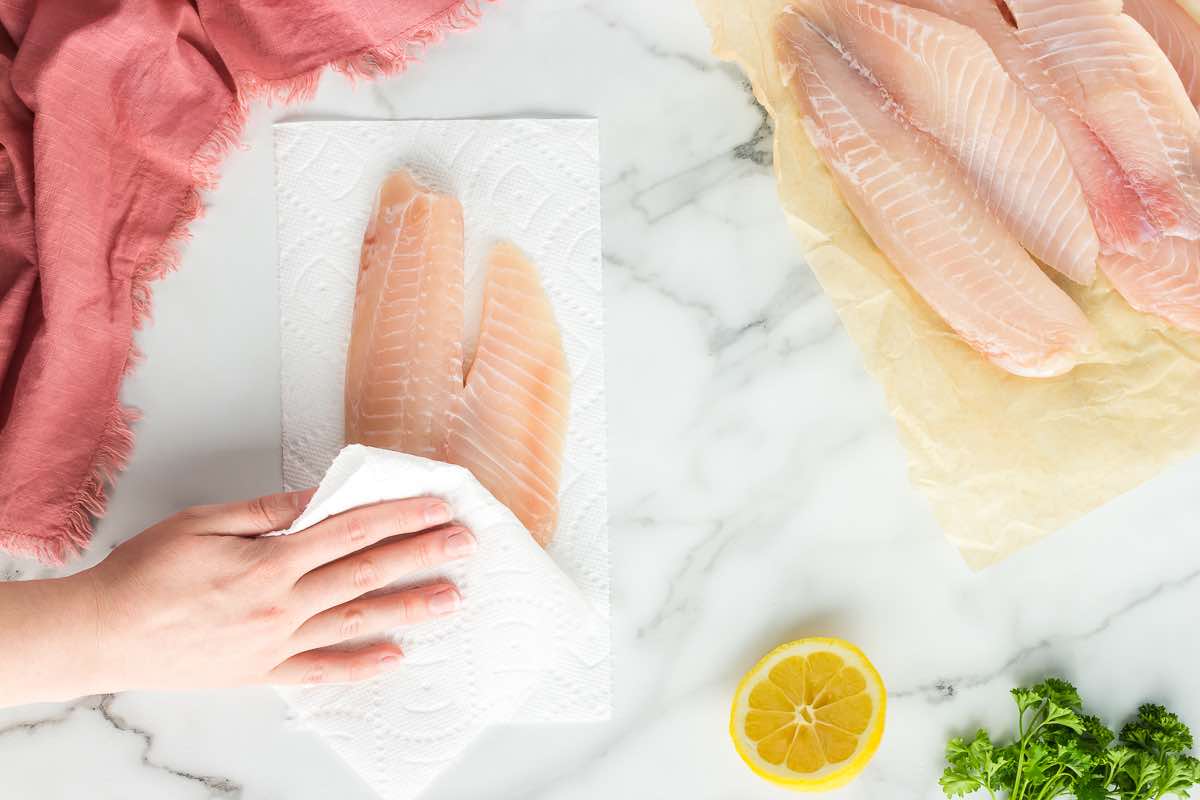 patting dry tilapia fillets with a paper towel.