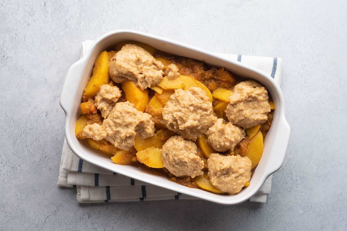 assembled peach cobbler with biscuit topping dropped on top.