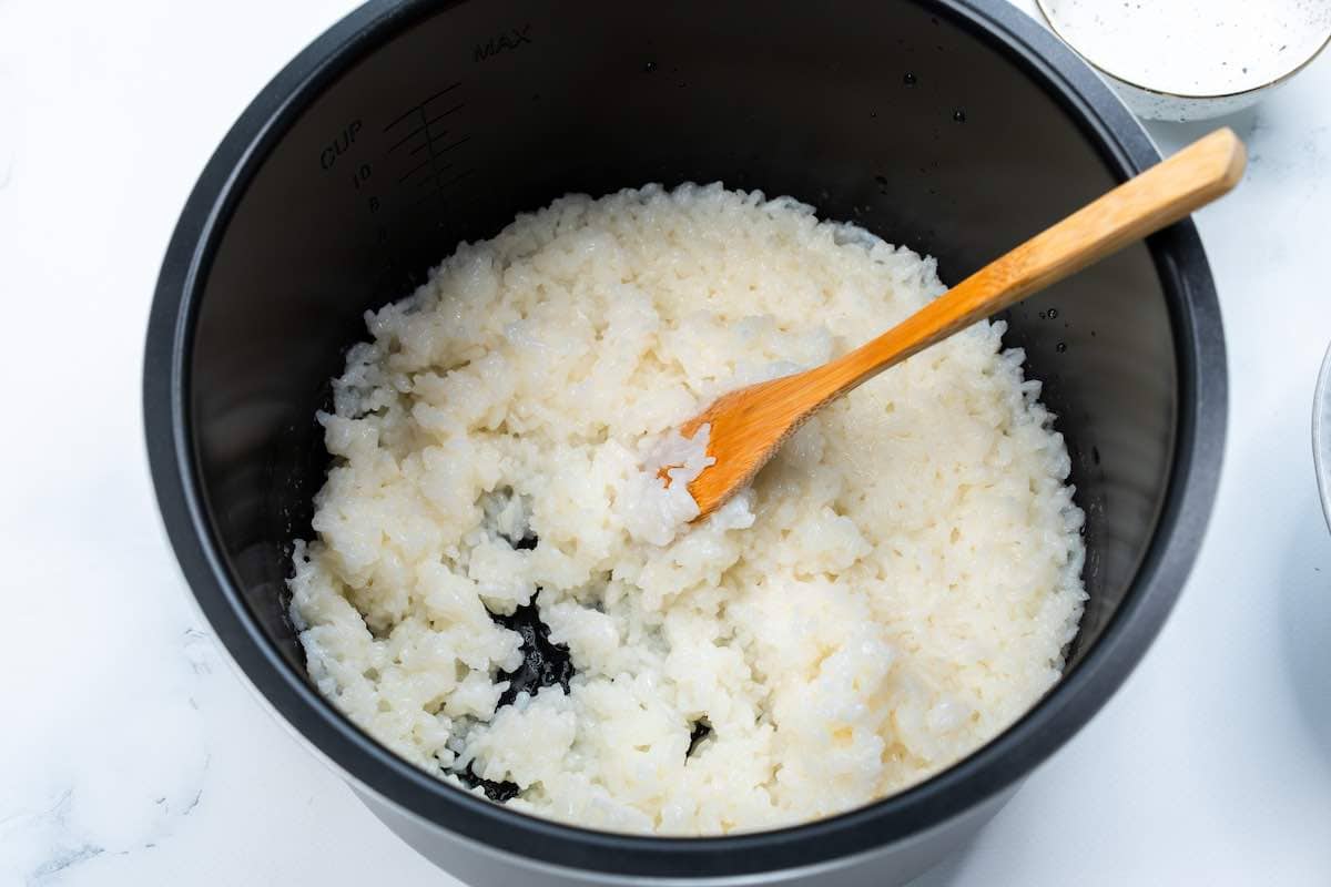 fluffing rice with a wooden spoon in the Instant Pot.