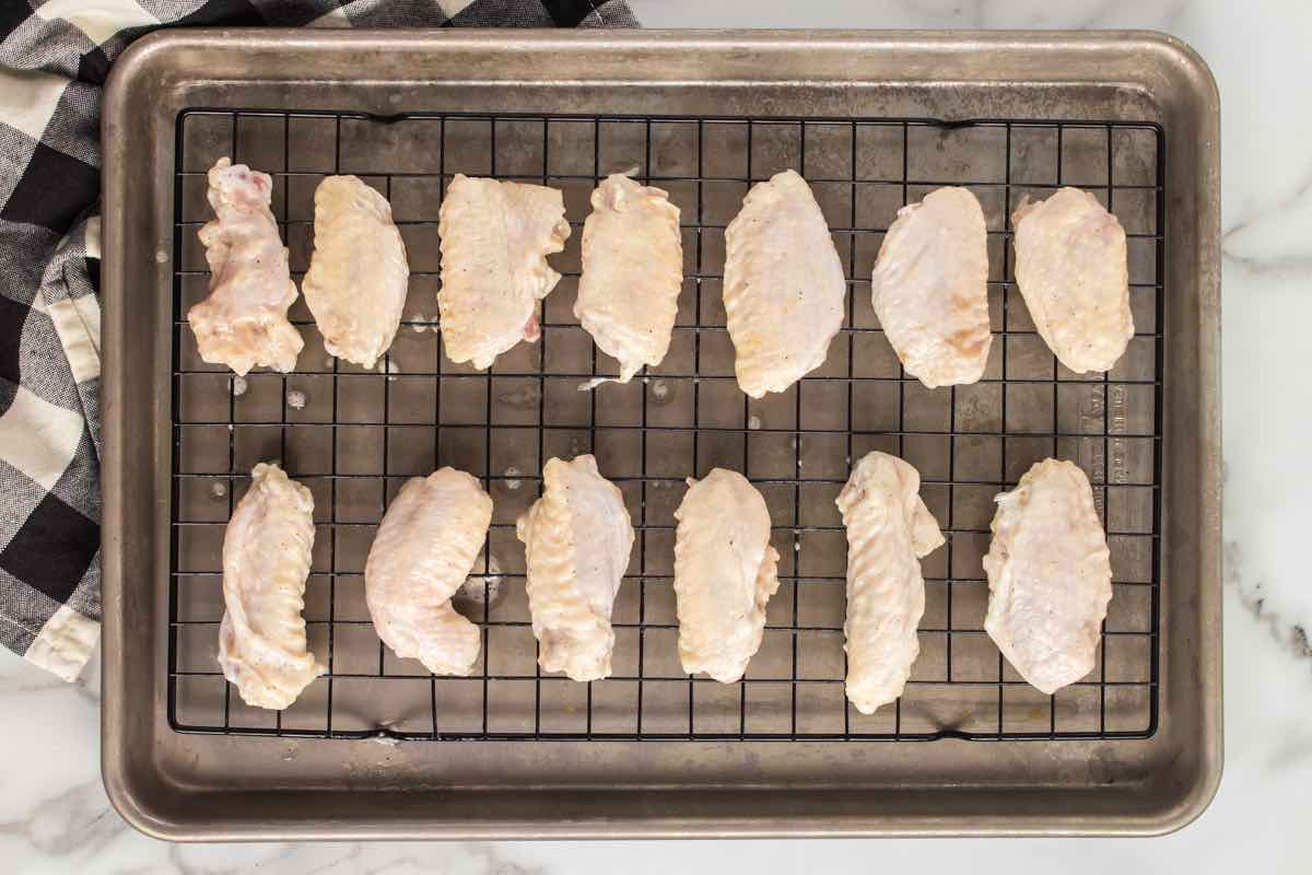 seasoned raw chicken wings on a wire rack.