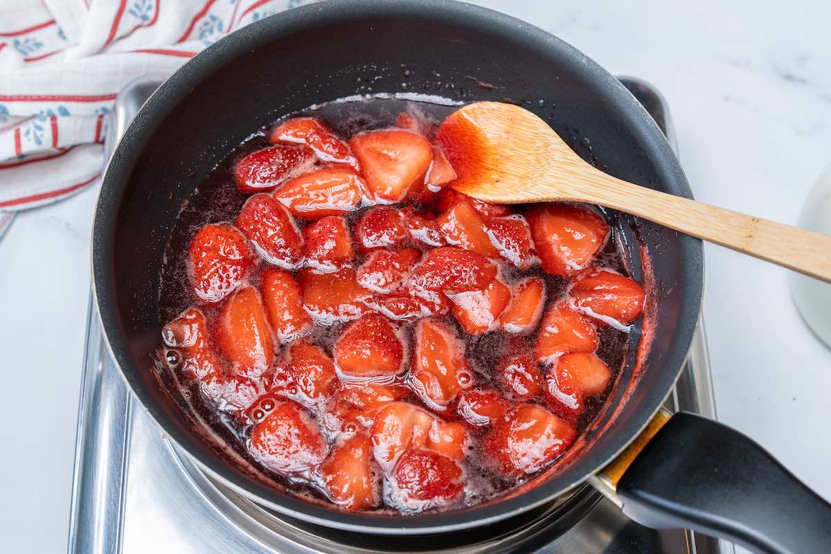strawberries, sugar, and water simmering in a saucepan.