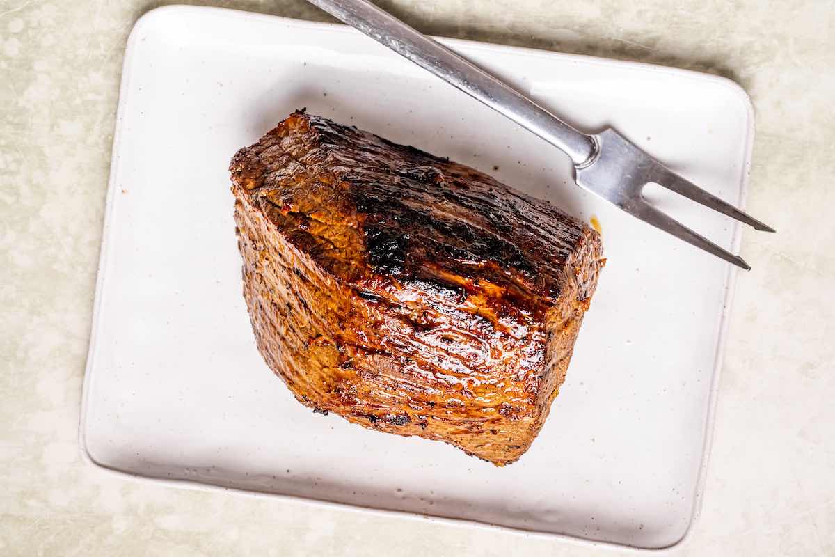 grilled tri tip steak resting on a board.