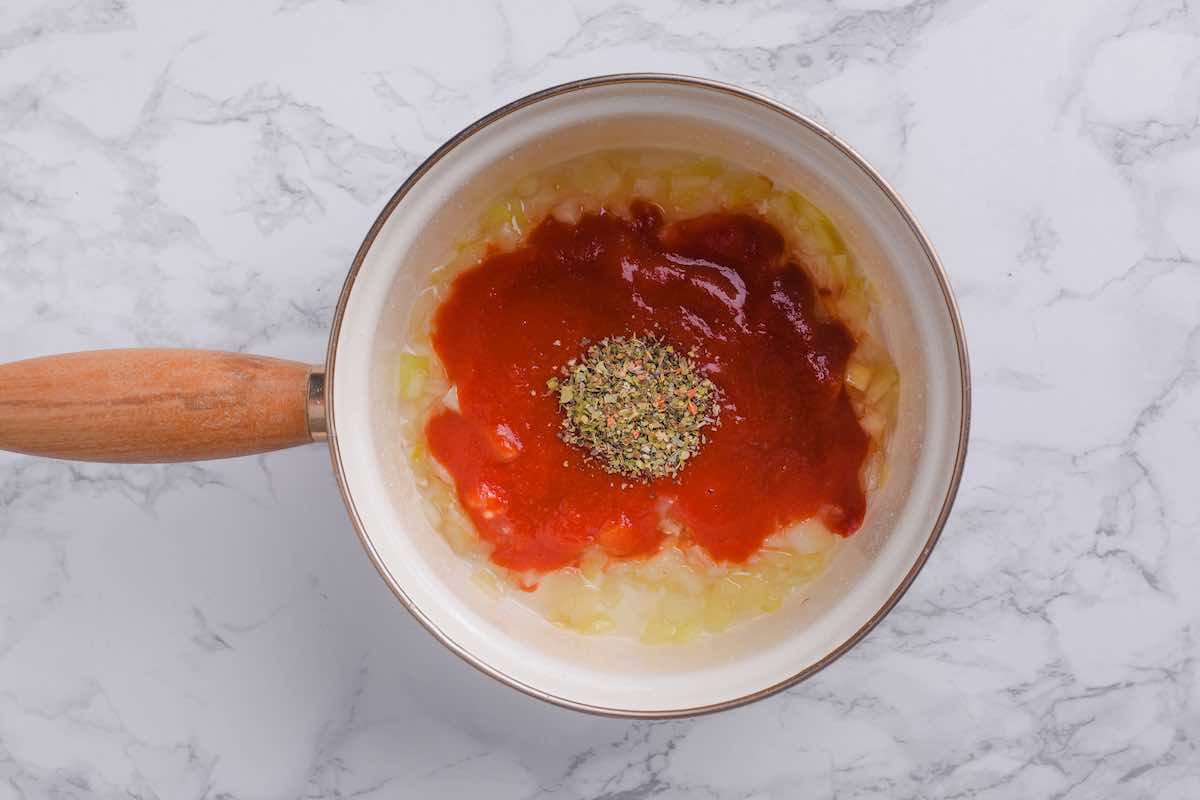 tomatoes, garlic, onion, olive oil, and Italian seasoning in a pot.