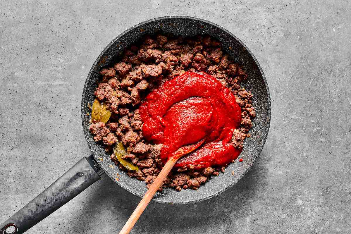 ground beef in a skillet with tomato sauce.
