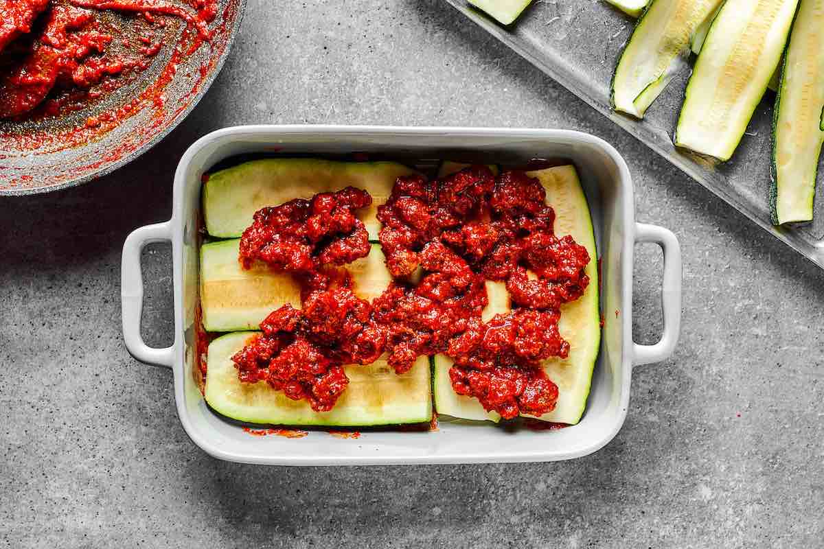 layering zucchini lasagna with ground beef mixture.
