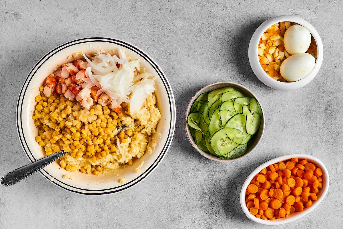 mixing corn, ham, and onion into mashed potatoes.