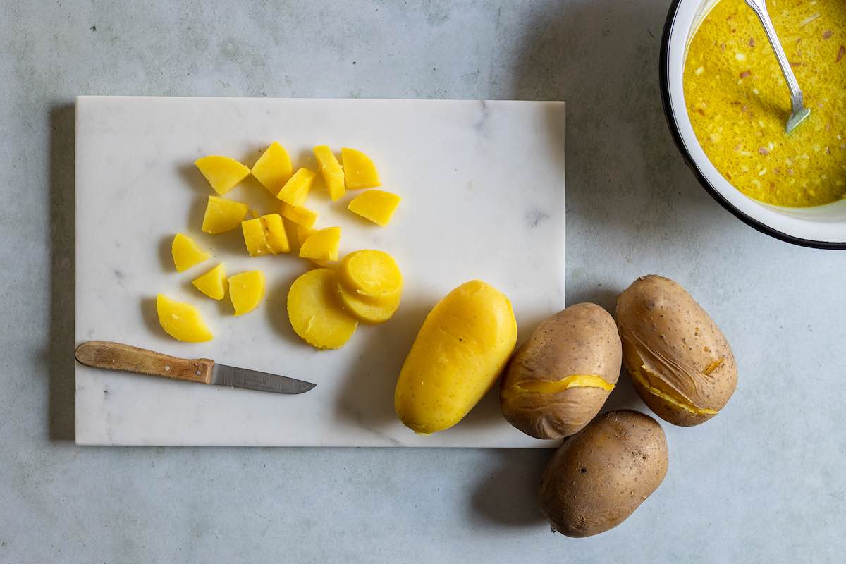 diced cooked and peeled potatoes on a chopping board.