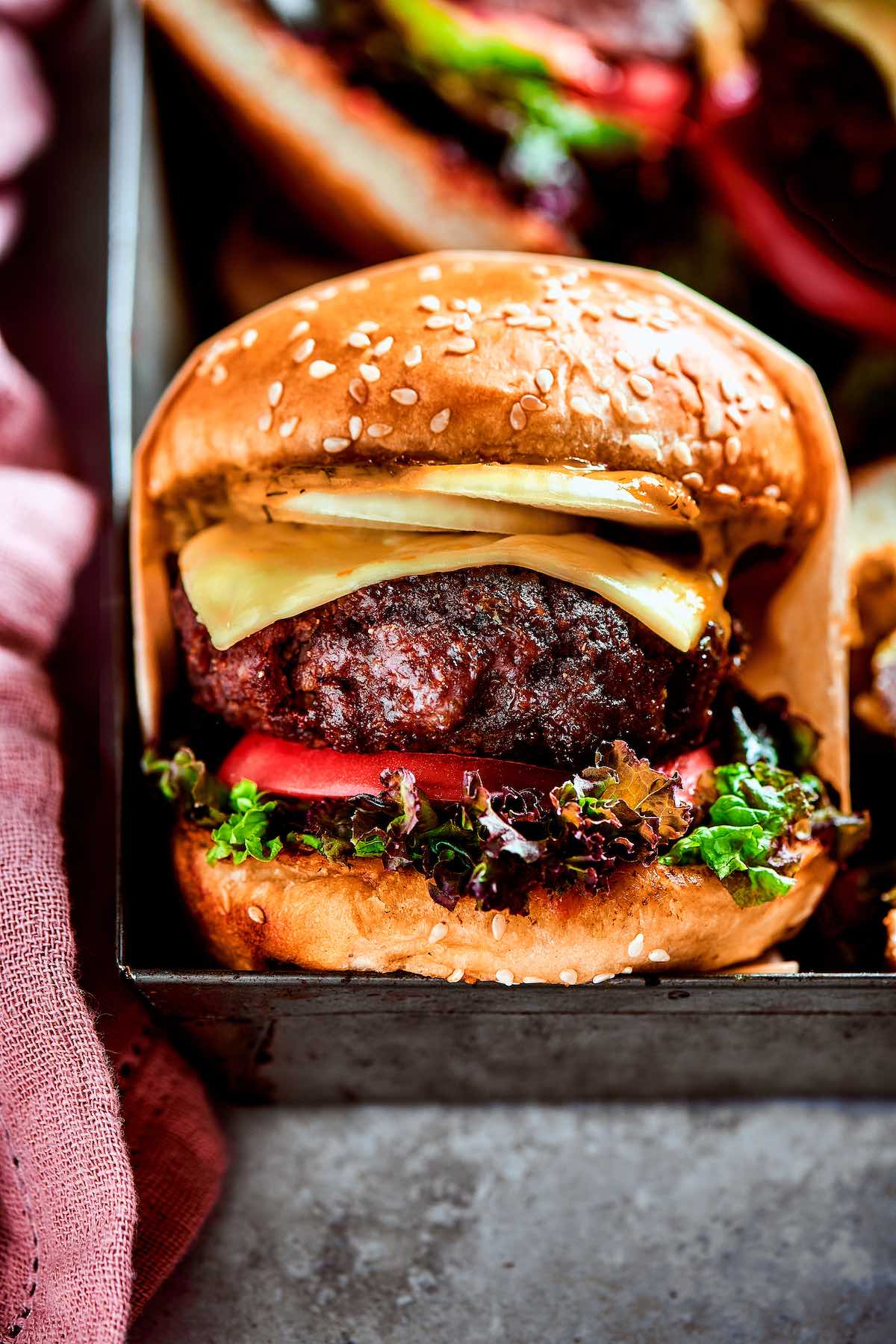 bison burgers in a burger bun with cheese, tomato, and lettuce.