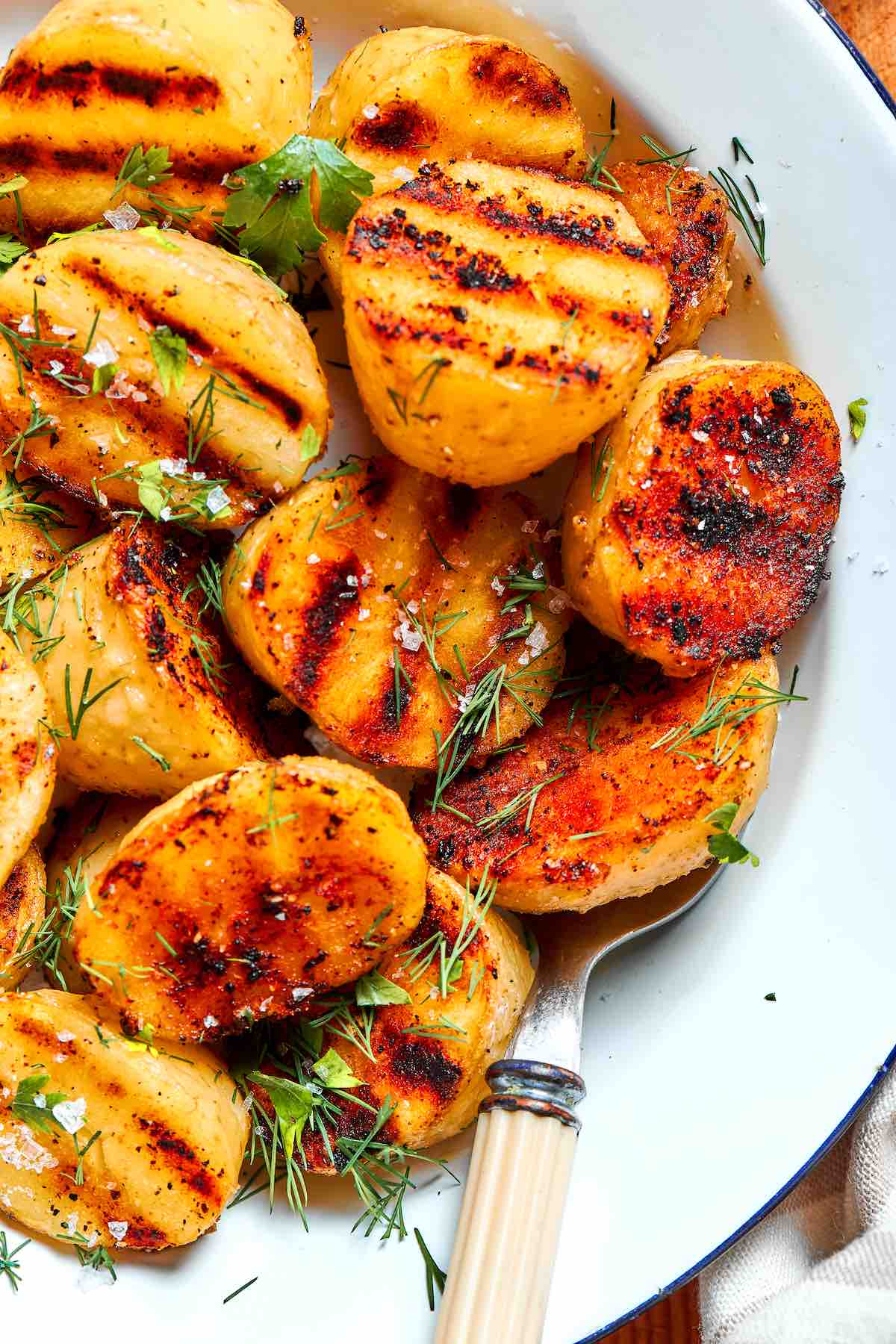 grilled potatoes in a bowl with sea salt and fresh herbs.