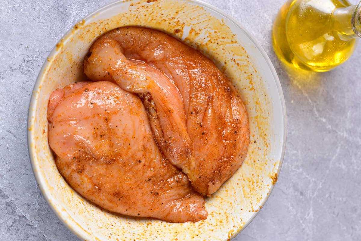 seasoned raw chicken breasts in a bowl.