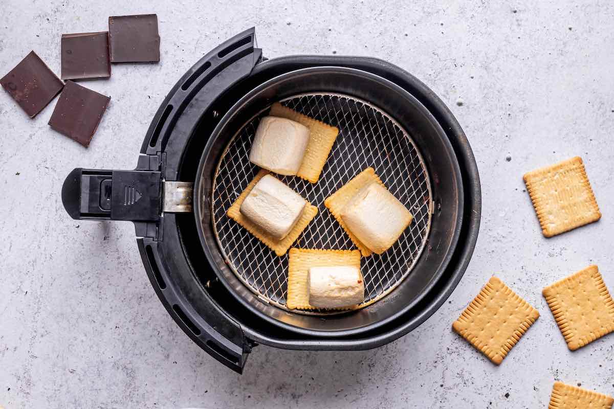 cooked marshmallows on graham crackers in the air fryer basket.