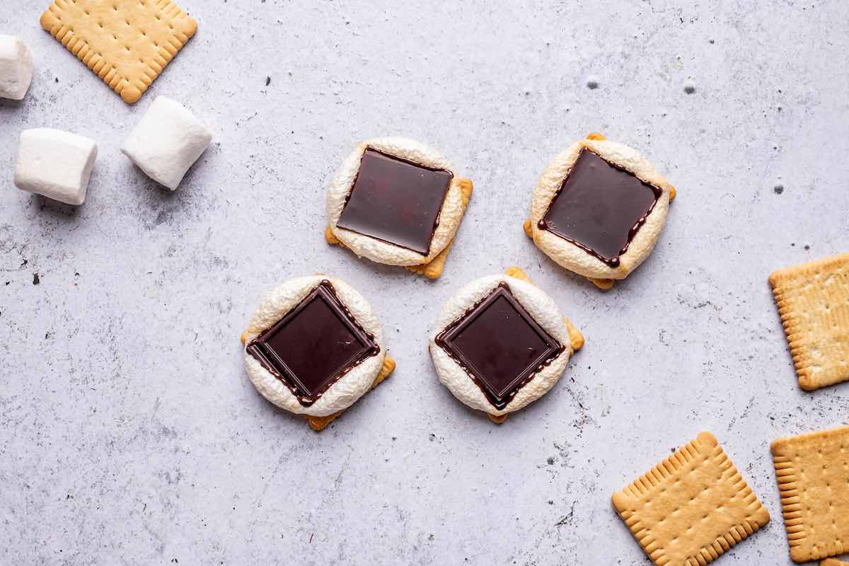 adding chocolate on top of each warm marshmallow.