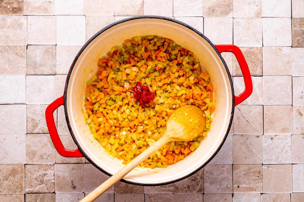 tomato paste added to a Dutch oven with sauteed vegetables.