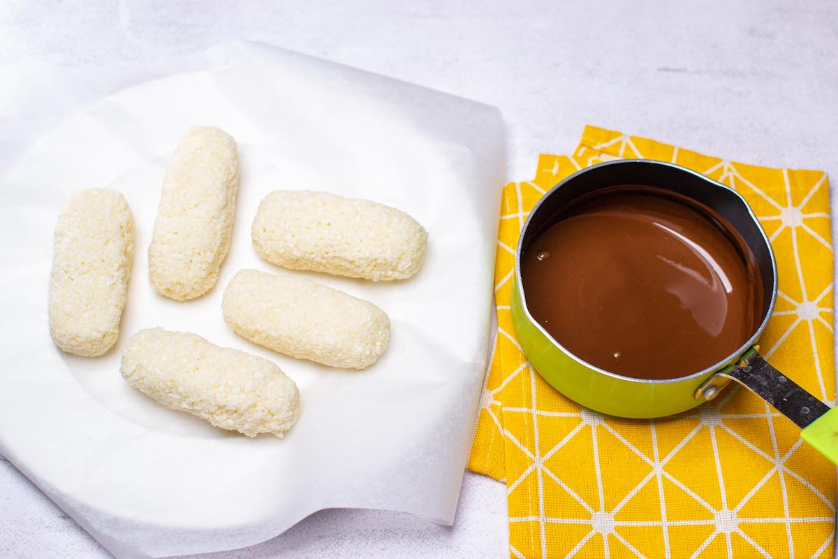 dipping coconut bars in melted chocolate.