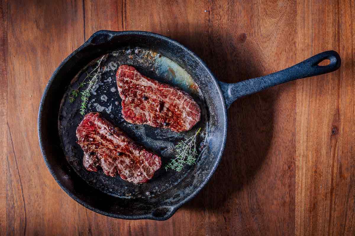pan-searing flank steak in a skillet.