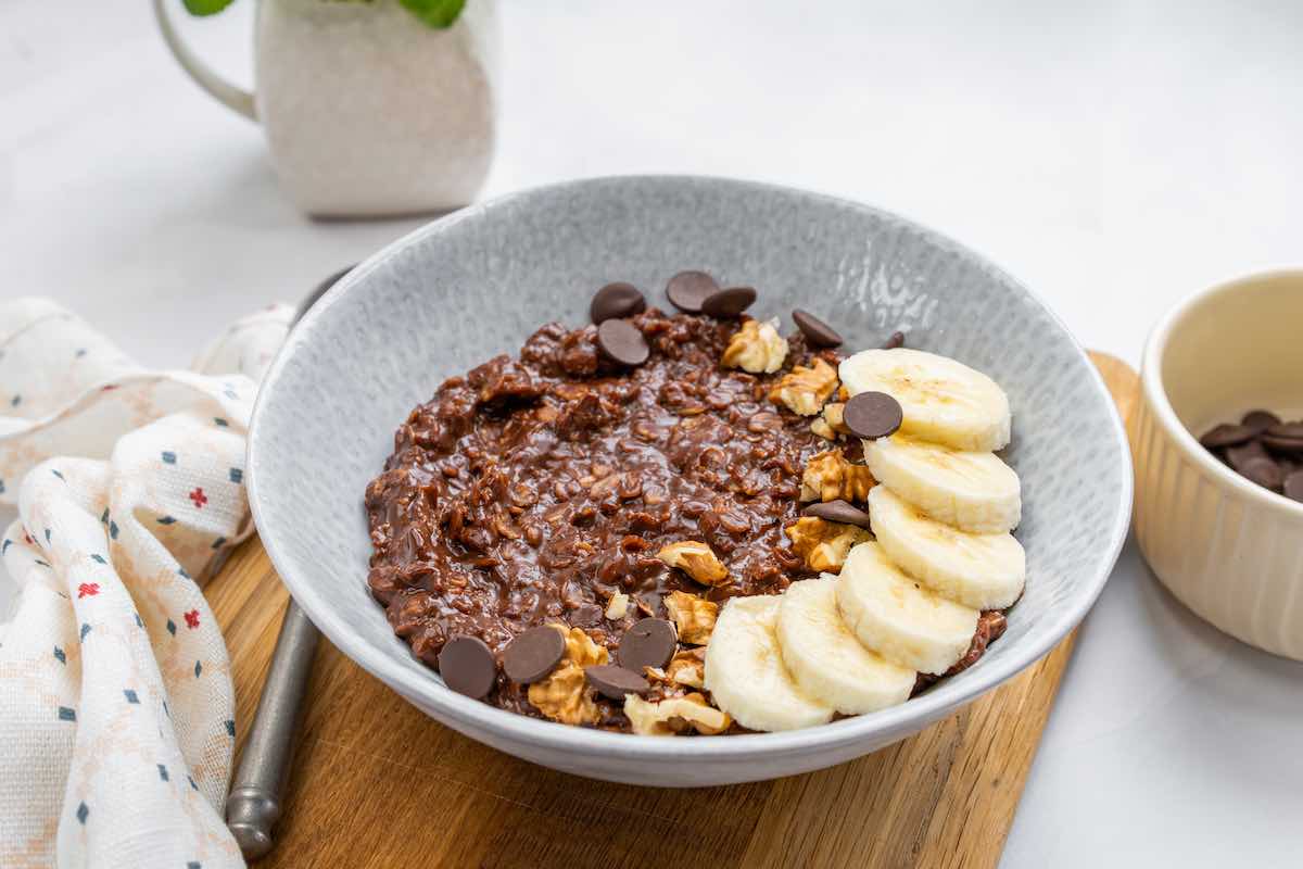 bowl of chocolate oatmeal with sliced banana and chocolate chips.