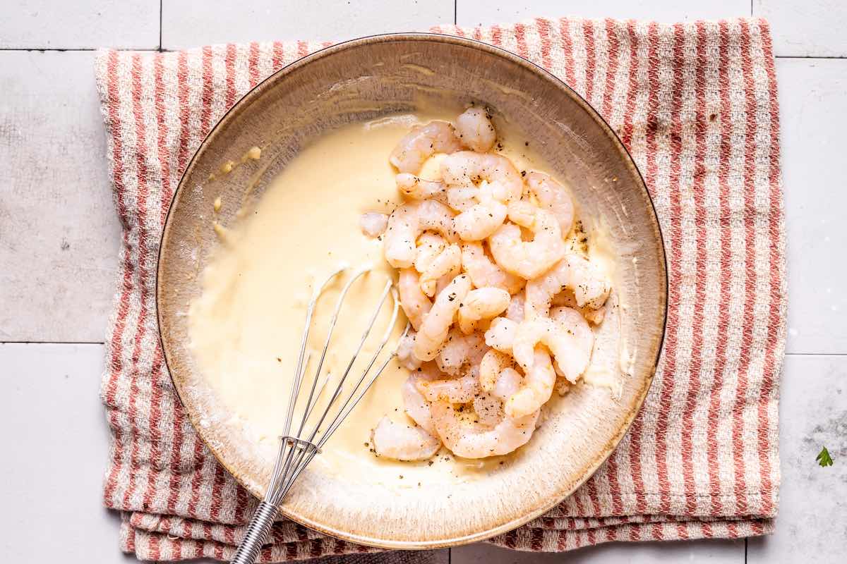 raw shrimp mixed with batter in a bowl.