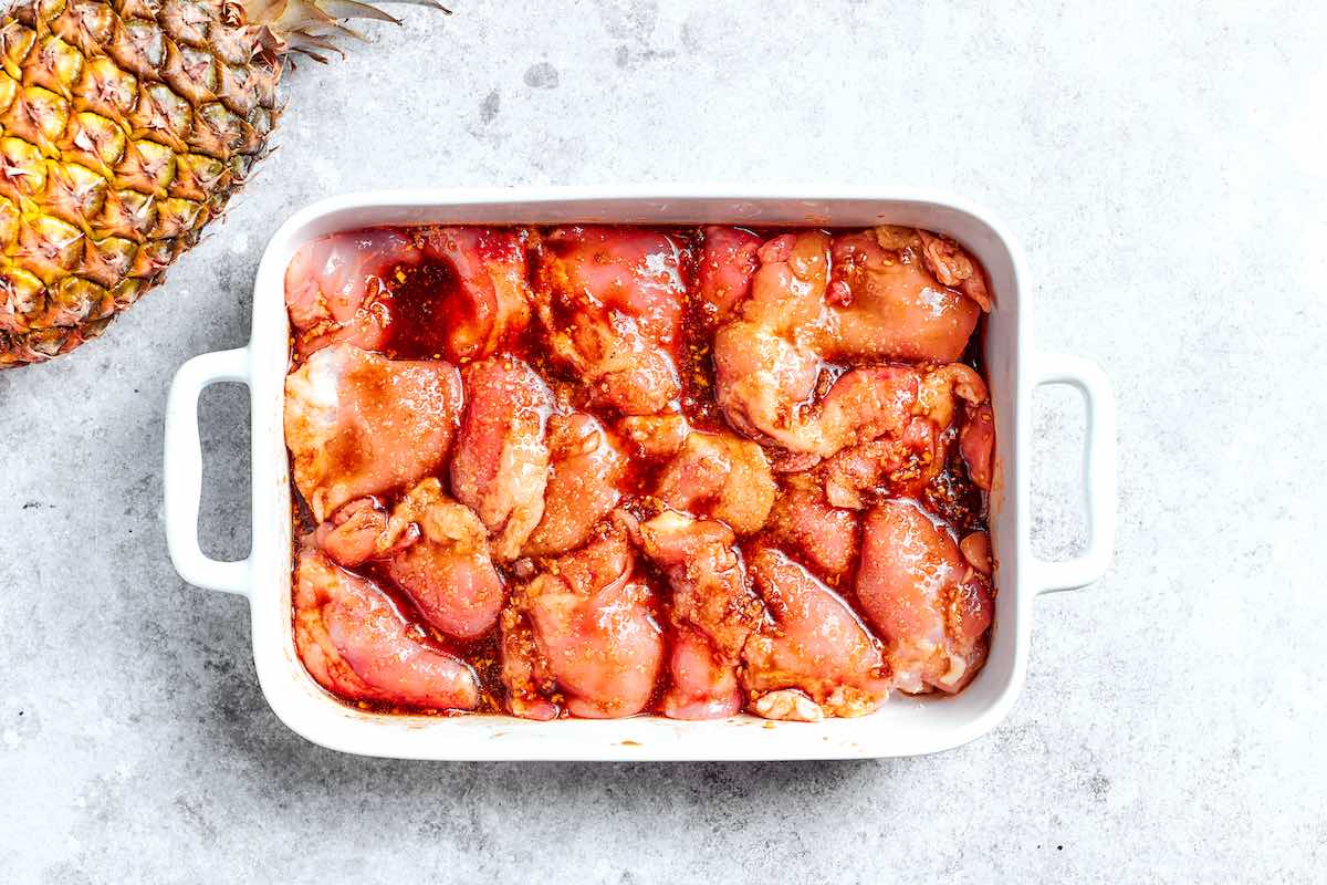 raw chicken thighs in teriyaki marinade in a baking dish.