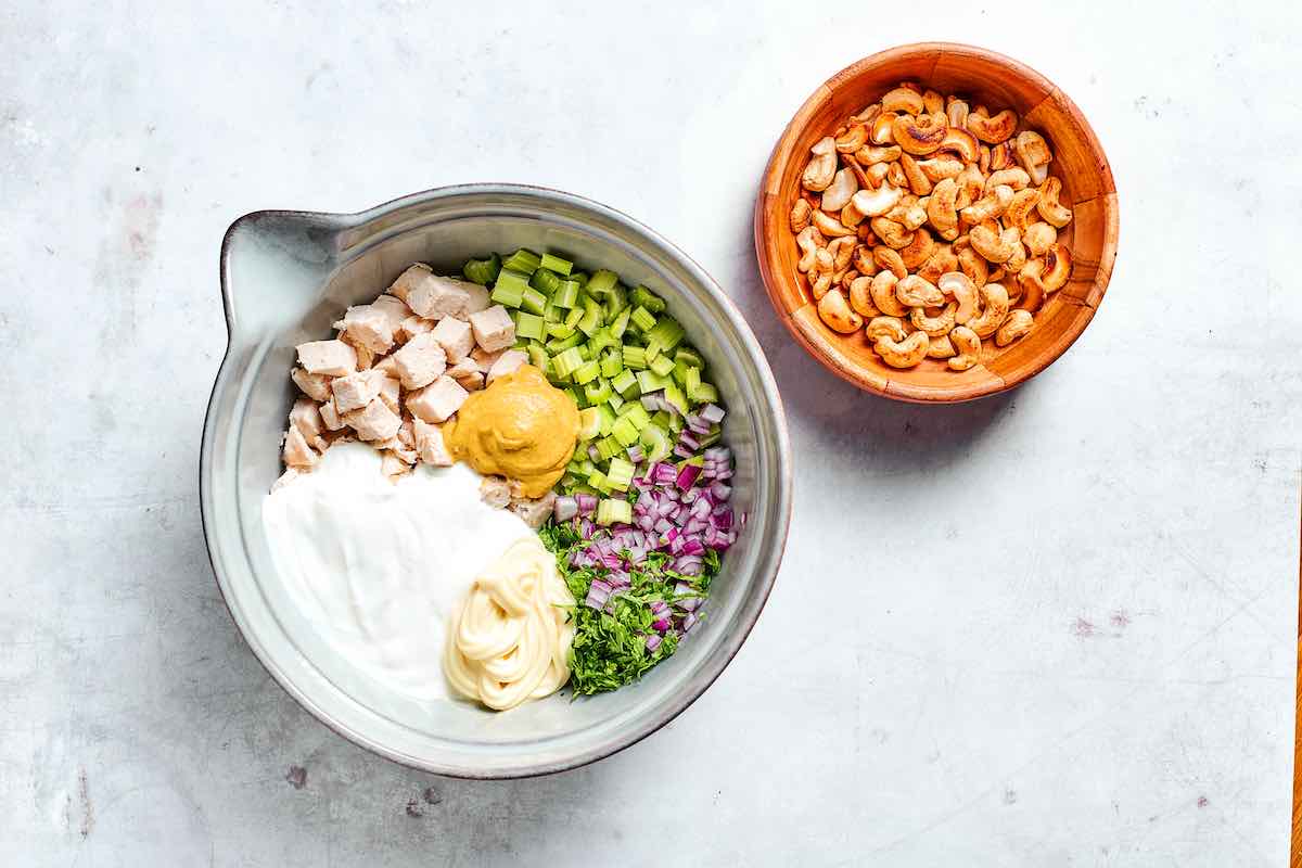 chicken, celery, mustard, mayo, greek yogurt, red onion, and parsley in a bowl.