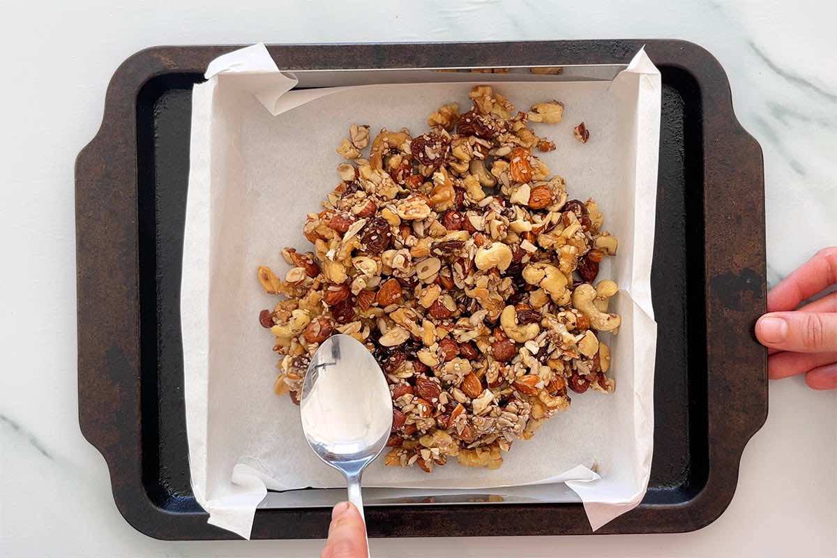 pressing down granola bar mixture in a pan.