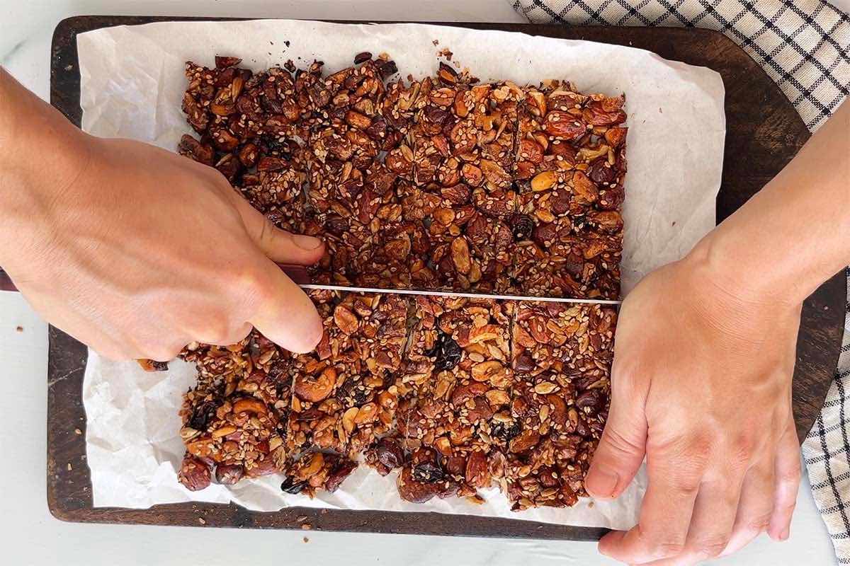 slicing keto granola bars on a chopping board.