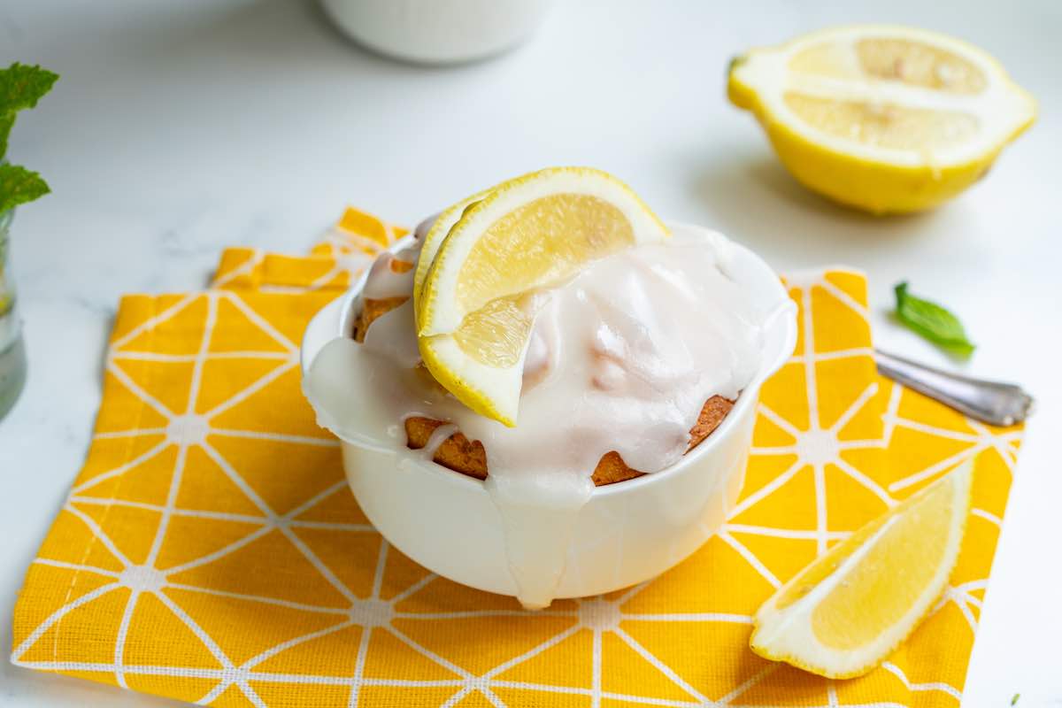 lemon mug cake with glaze and sliced lemons.