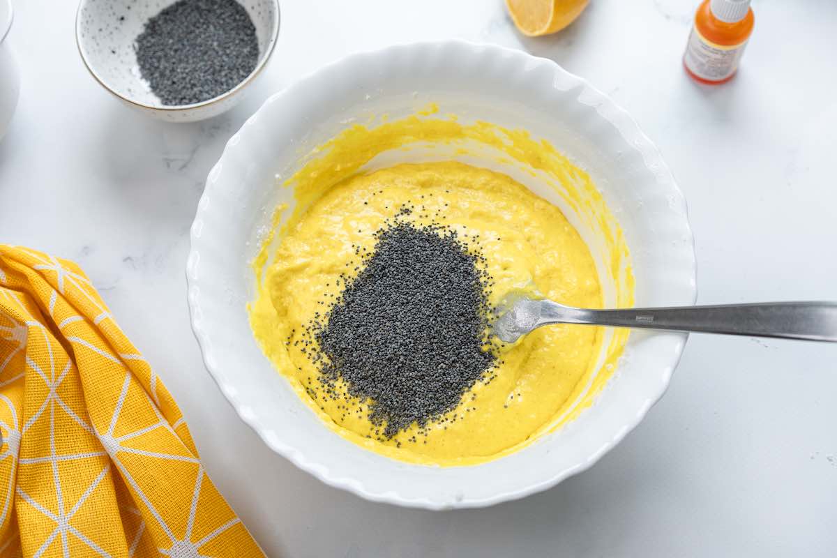 cake batter in a bowl with poppy seeds folded through.