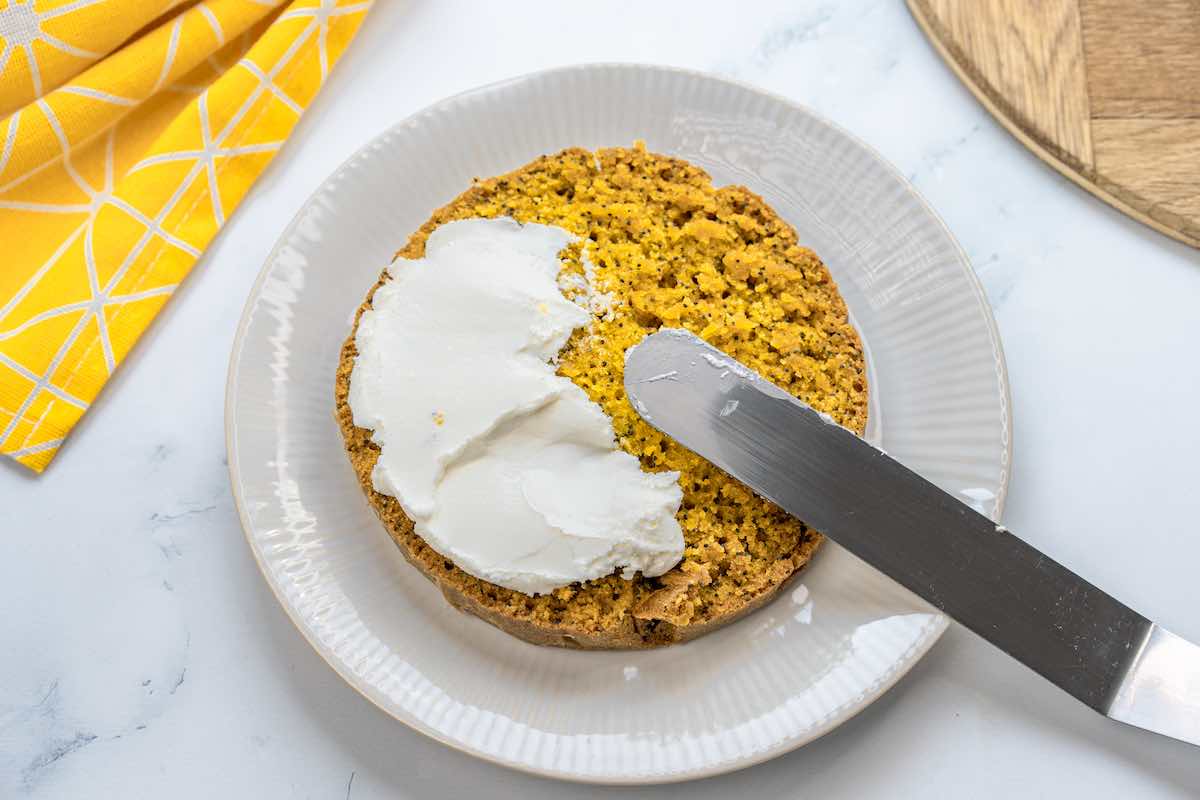 frosting a lemon poppy seed cake.