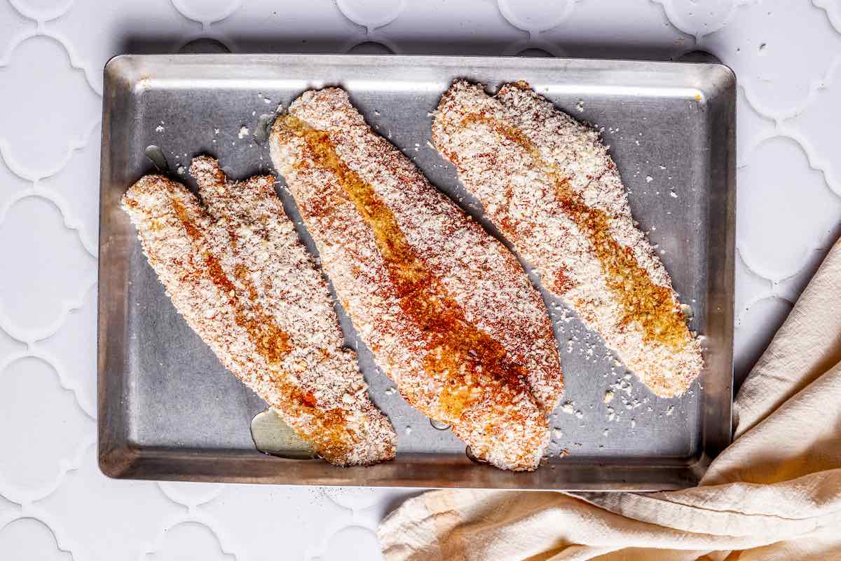 seasoned raw tilapia fillets with a drizzle of olive oil on top.