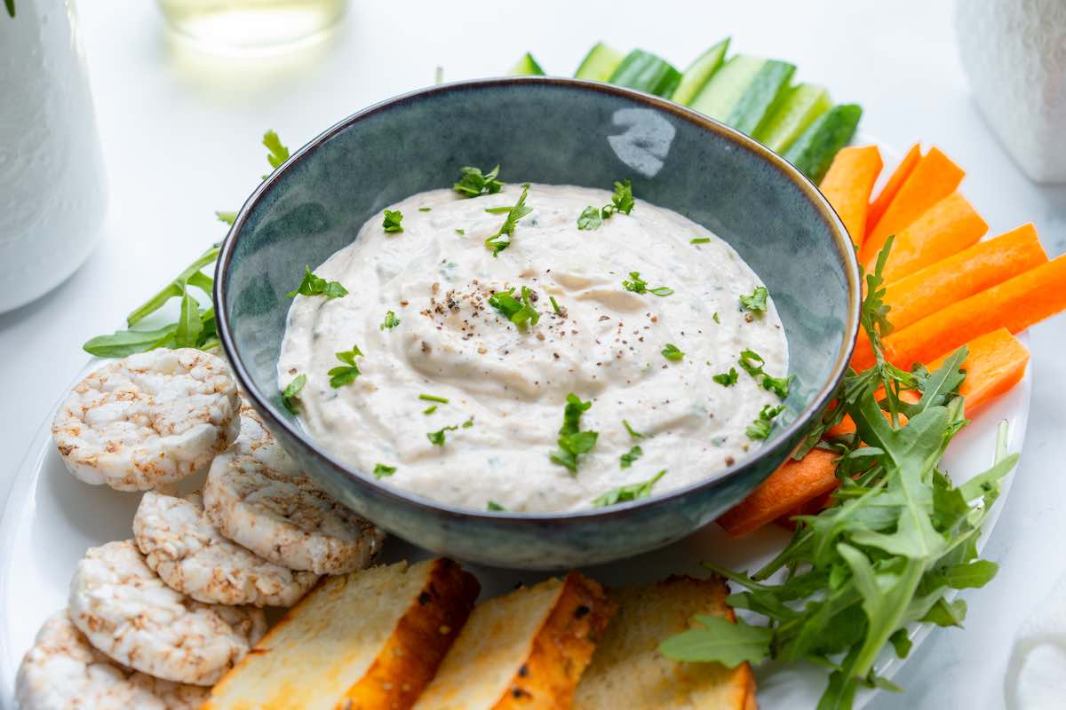 bowl of salmon dip with crackers and vegetables.