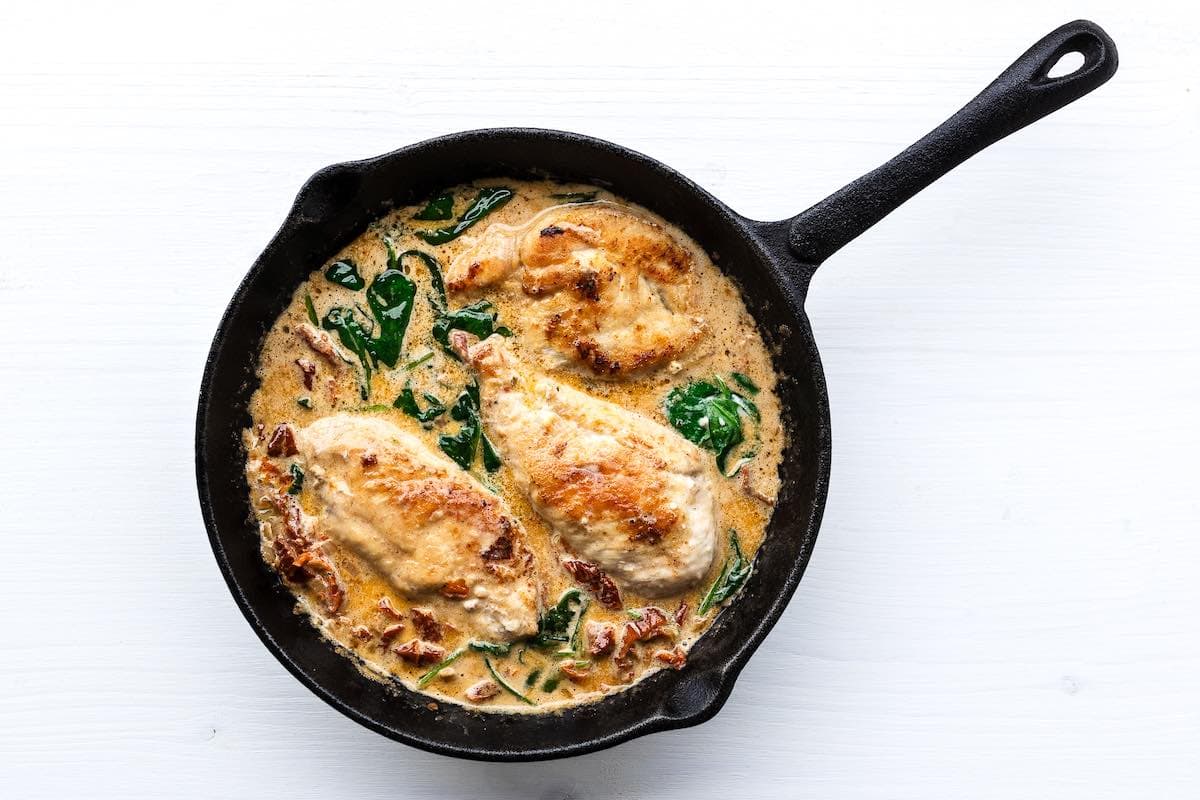 chicken in a skillet with Tuscan sauce.