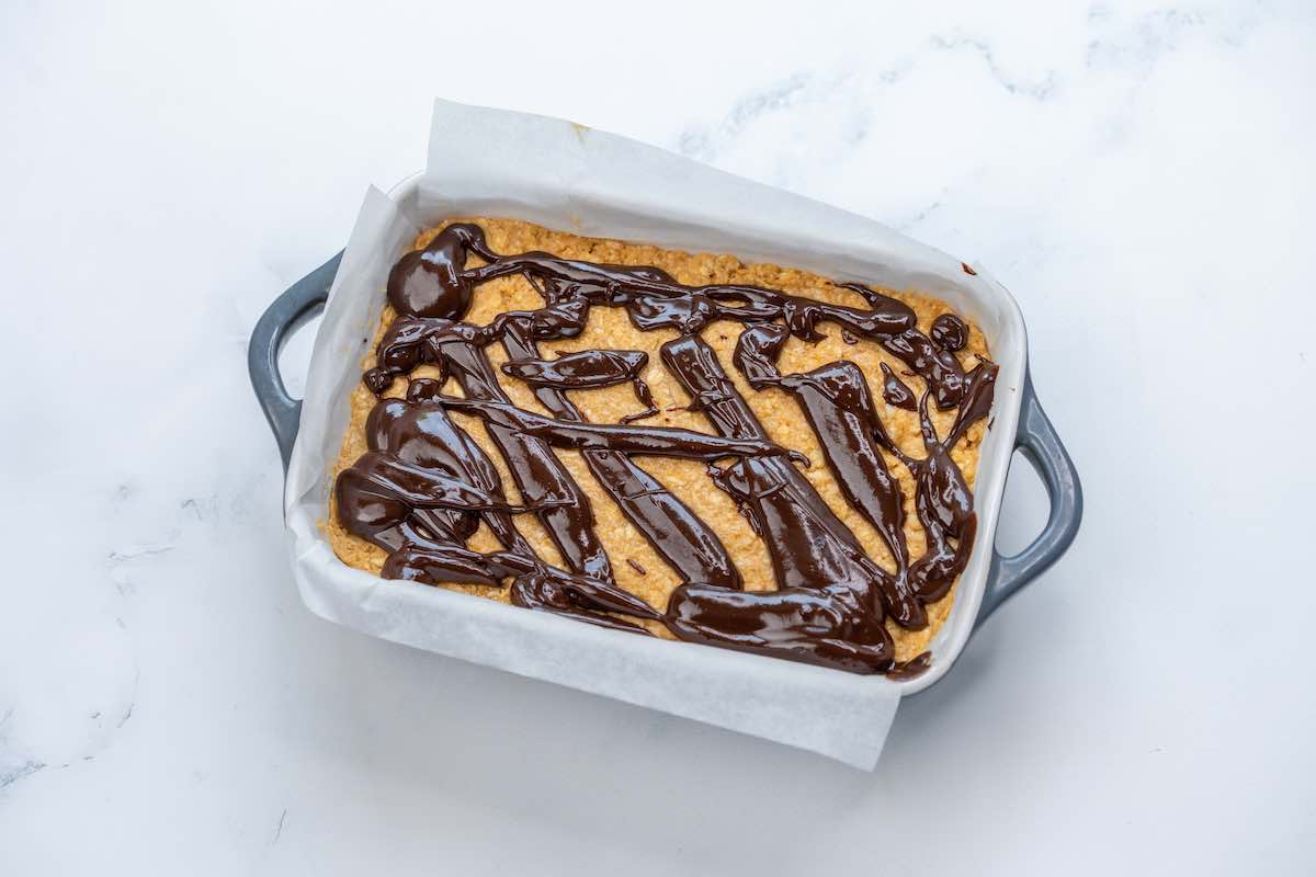 baking dish with protein bar mixture and chocolate melted on top.