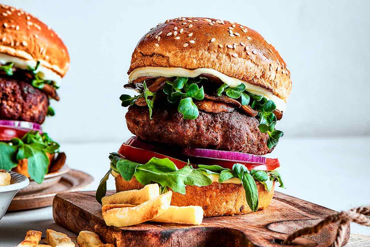 assembled wagyu burgers with lettuce, onion, tomatoes, bacon, and mayonnaise.