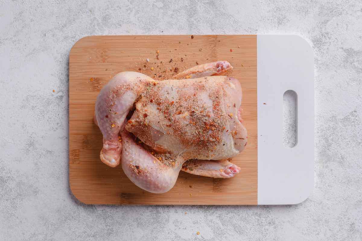 rubbing seasonings on raw Cornish game hens.