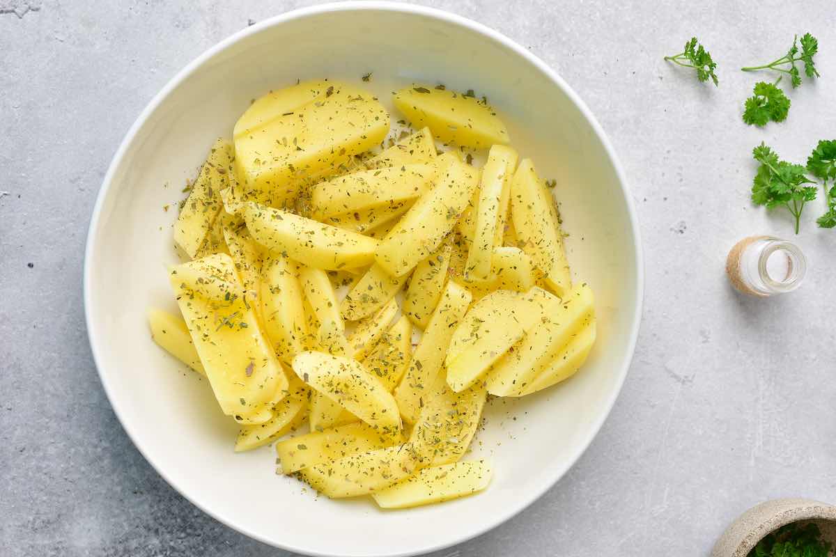 raw seasoned fries in a bowl with Italian seasoning and salt.