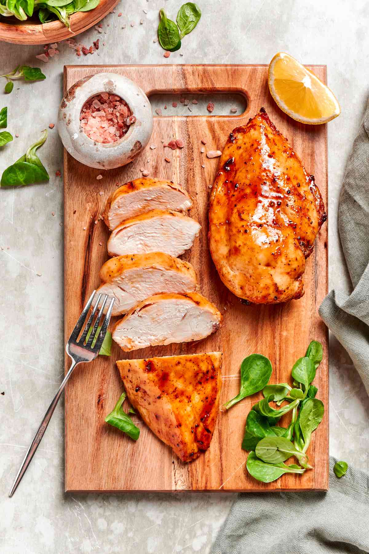 sliced air fryer frozen chicken breast on a board.