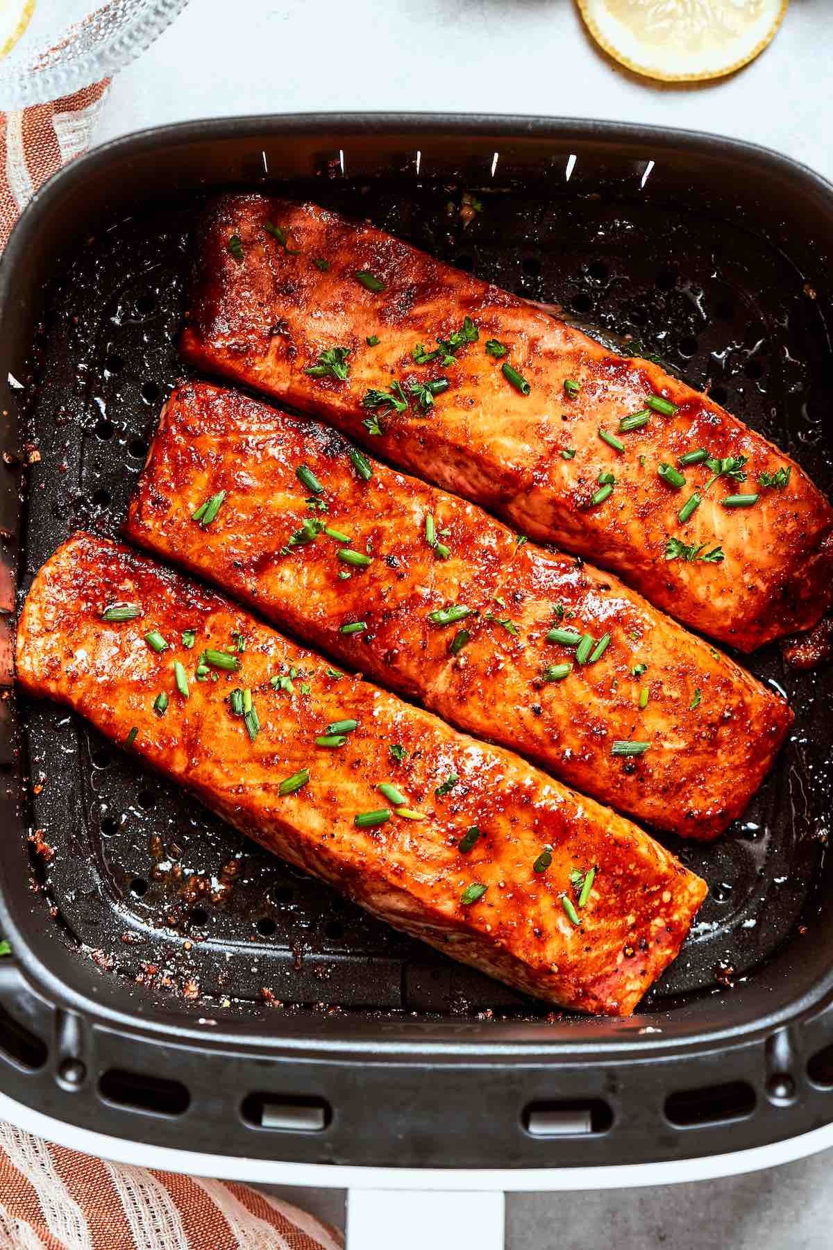 frozen salmon in air fryer with fresh herbs on top.