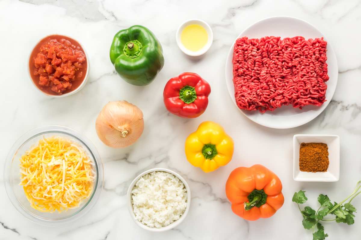 ingredients needed for healthy stuffed peppers- lean ground beef, bell peppers, shredded cheese, onion, taco seasoning, and diced canned tomatoes.