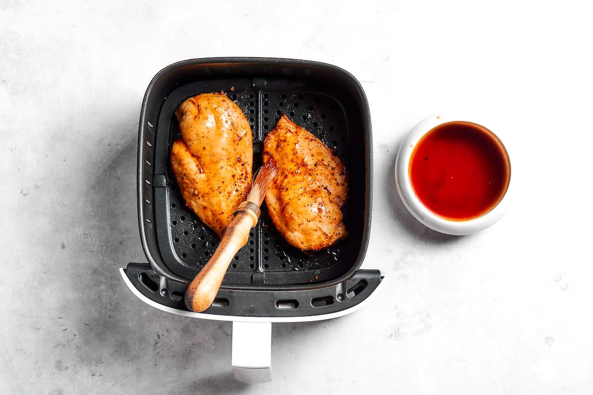 brushing sauce on air fried frozen chicken breast.