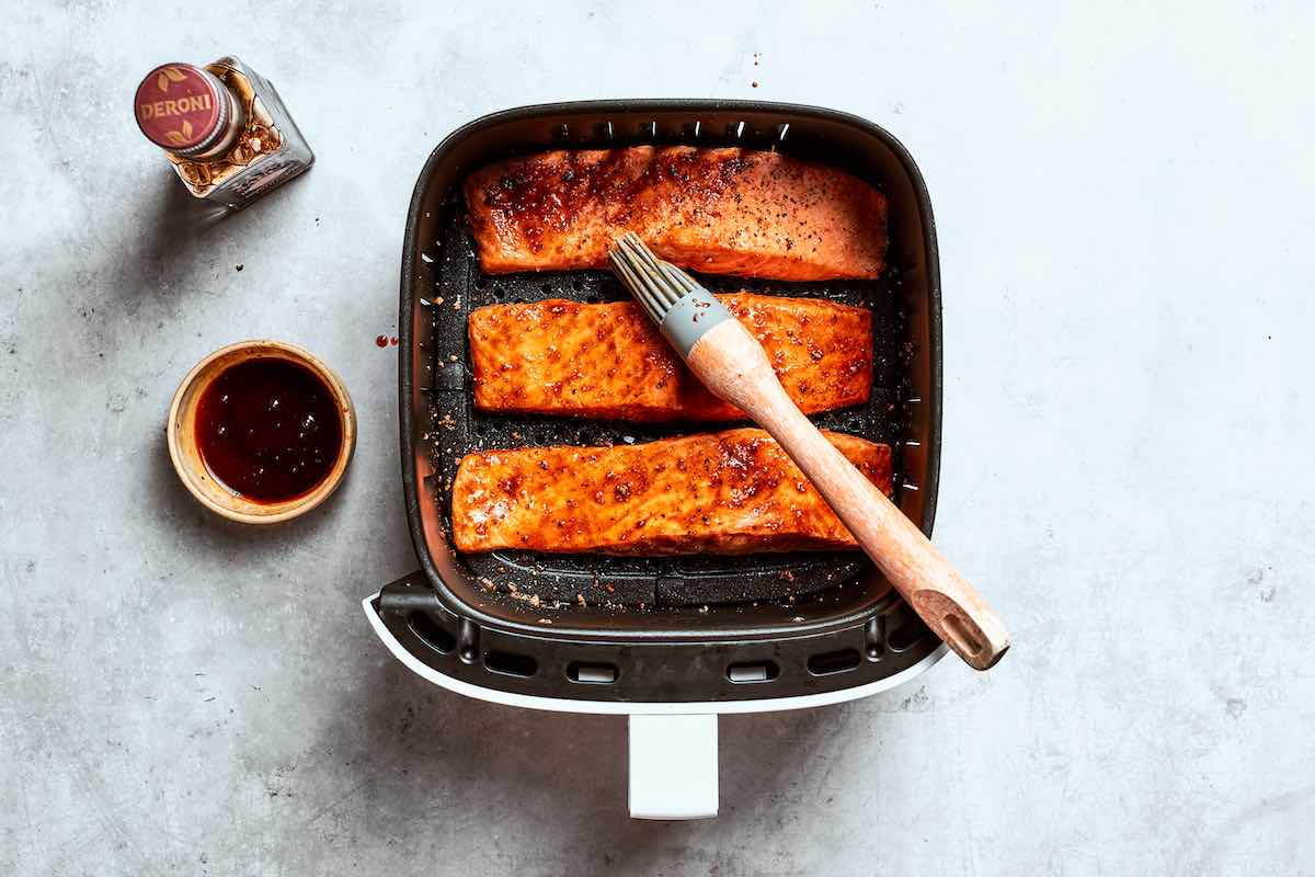 brushing par-cooked salmon with sauce.