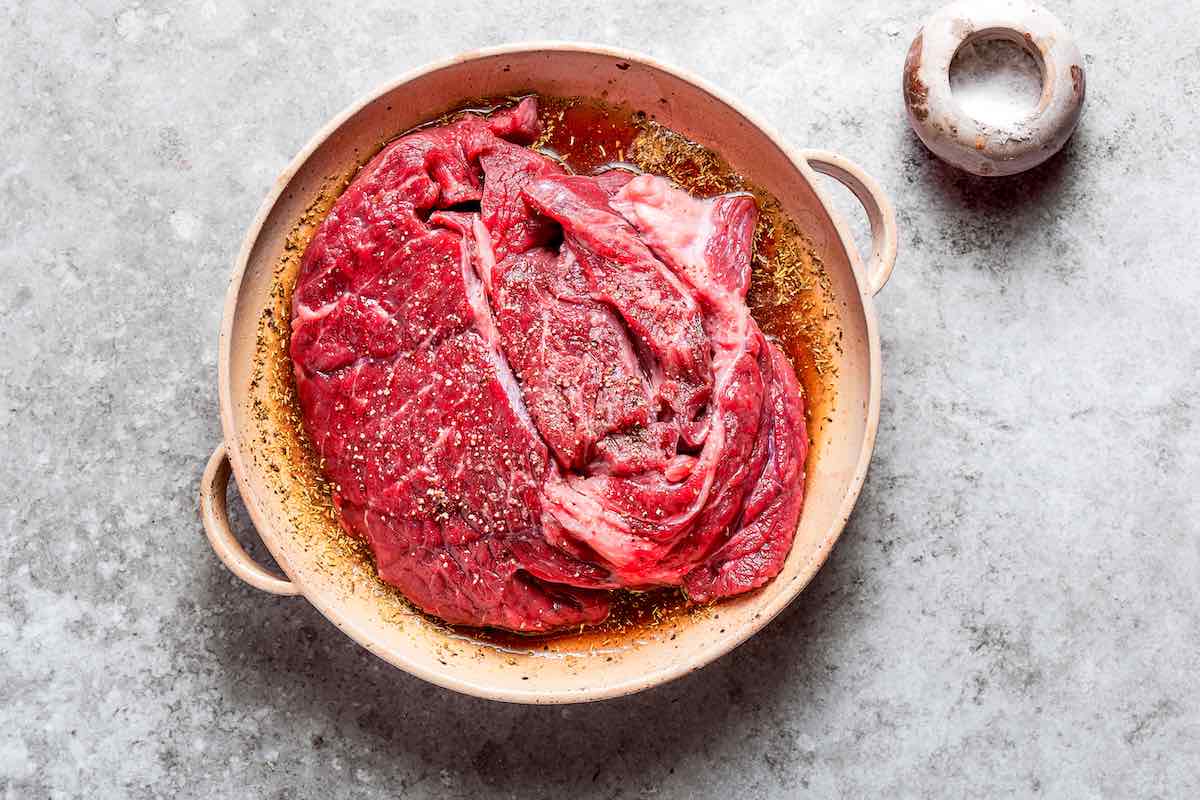 seasoned raw chuck roast in marinade.