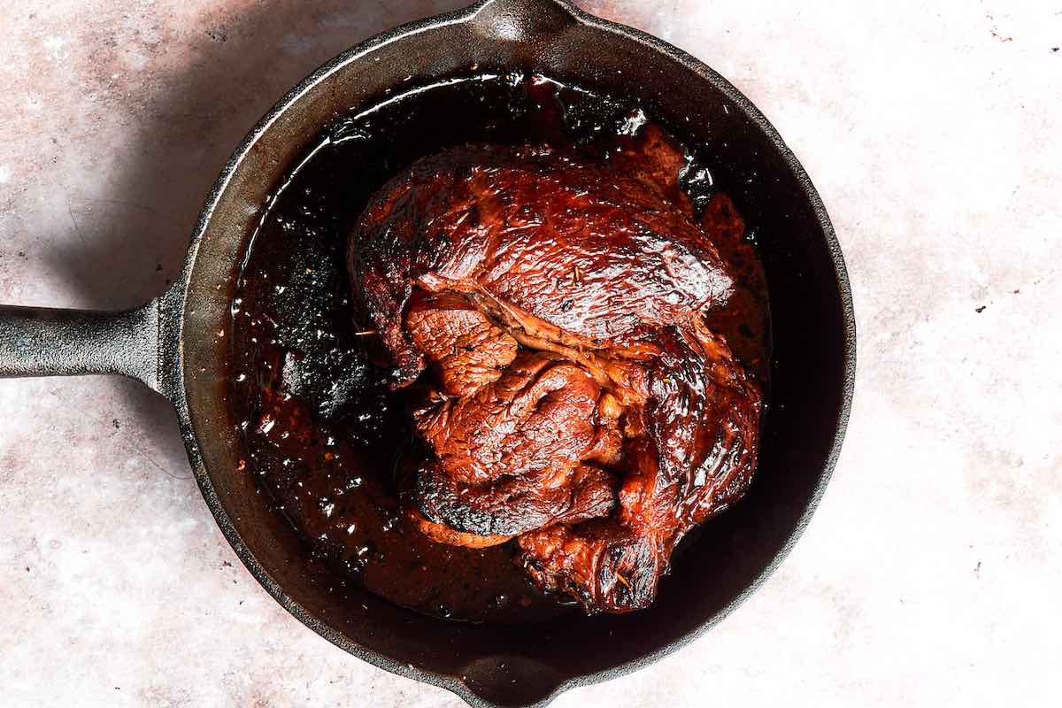 grilled chuck roast resting in a cast iron skillet.