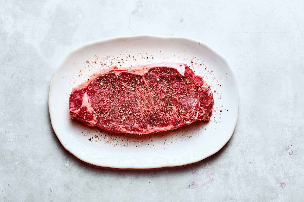 raw beef shoulder steak seasoned with salt and pepper.