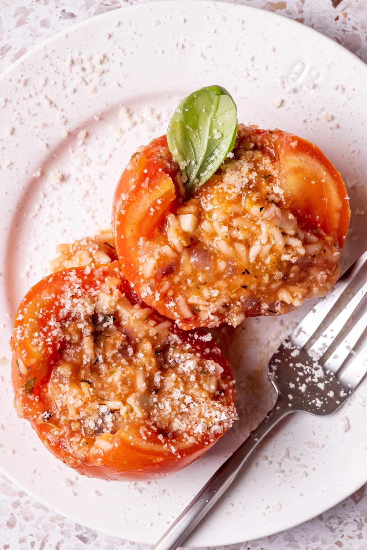 stuffed tomatoes on a plate with freshly grated parmesan cheese on top.