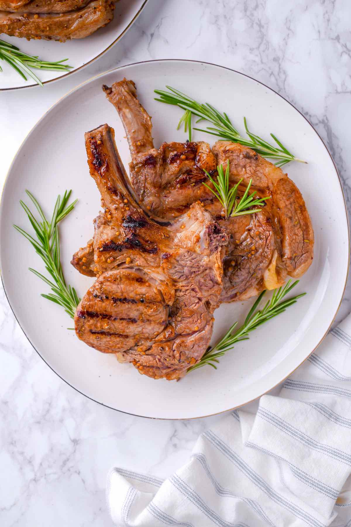 pan seared veal chops on a plate with Rosemary.