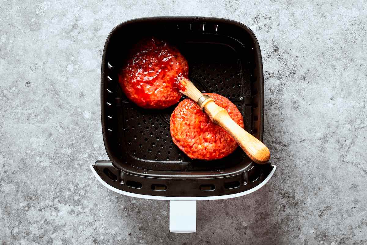 ketchup slathered over frozen burger patties in the air fryer.