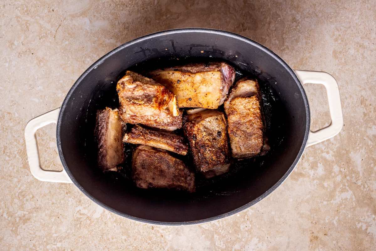 searing short ribs in a pot.