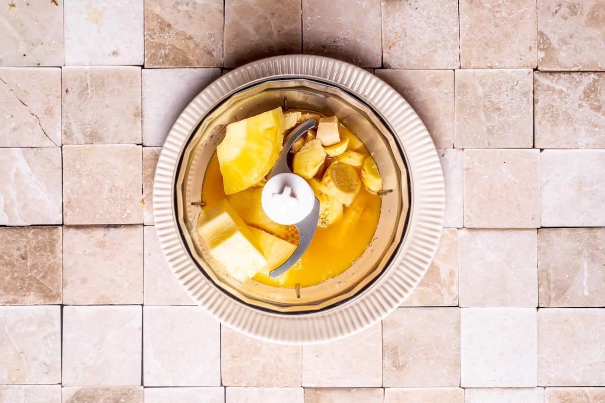 blender with pineapple, ginger, orange juice, and lime juice.